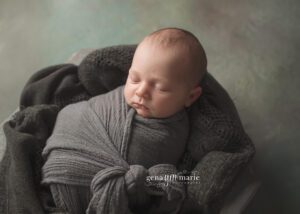 sleeping newborn wrapped in grey blanket
