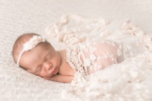 newborn girl surrounded in cream lace